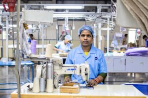 Portrait of a focused female textile worker operating a sewing machine in a factory setting, showcasing industrial precision.