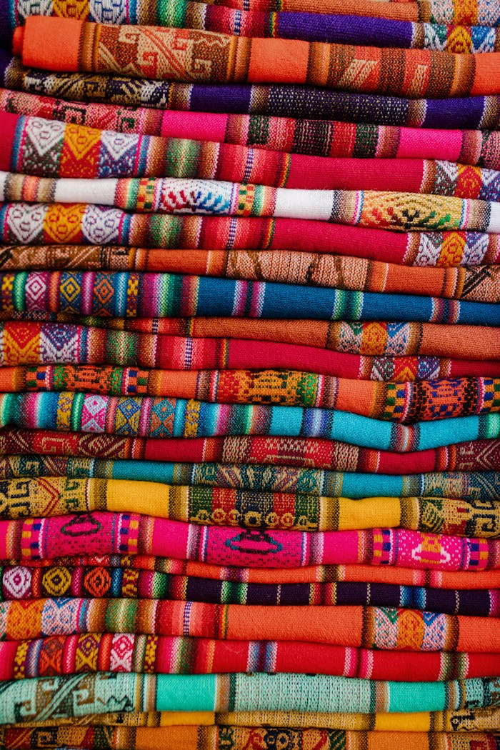 why-choose-us Vibrant, handwoven Peruvian fabrics intricately folded in a vertical arrangement showcasing cultural motifs.